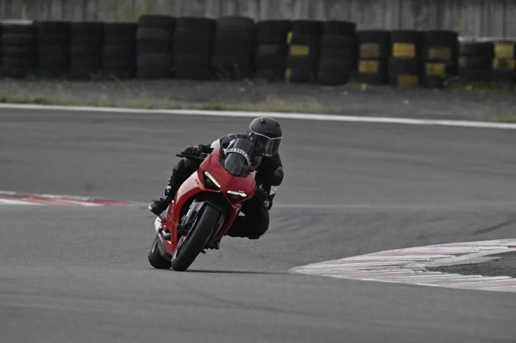 Motorcycle rider in black gear leaning into a corner on a red sportbike during a track session, showcasing top circuit bike racing training.