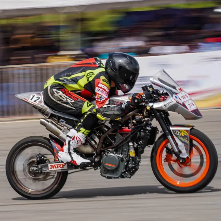 Motorcyclist in racing gear accelerating on a track during a high-speed GT bike racing event.
